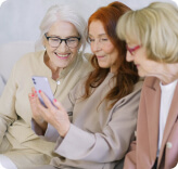 Three elderly women speaking over a phone via online conference app