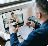 Employee speaking with teammate via laptop over online conference tool